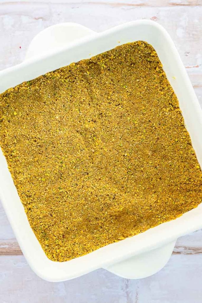 Pistachio crust pressed into an 8x8" pan.