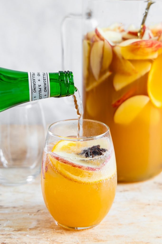 Sparkling water being poured into Apple Cider Sangria.