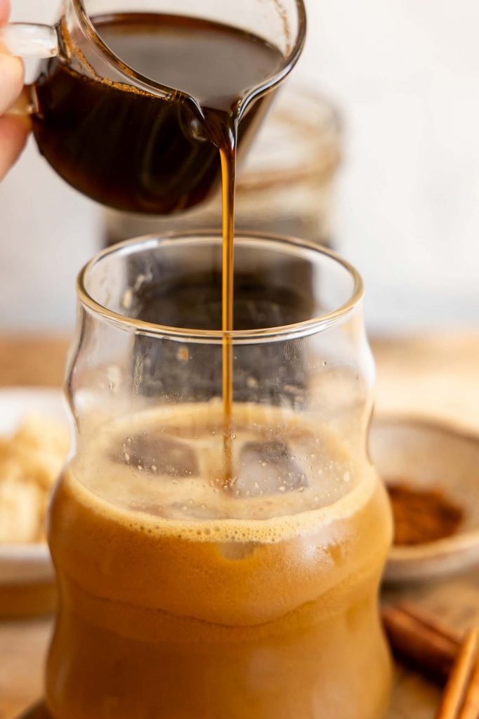 Brown sugar syrup being poured into coffee.