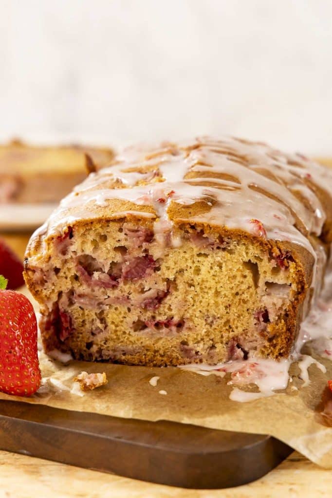 A loaf of strawberry bread on a cutting board.