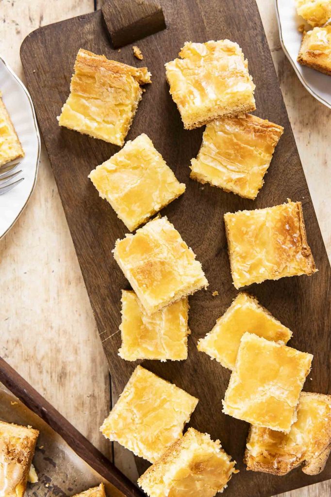 Gooey Butter Cake cut into squares on a cutting board.